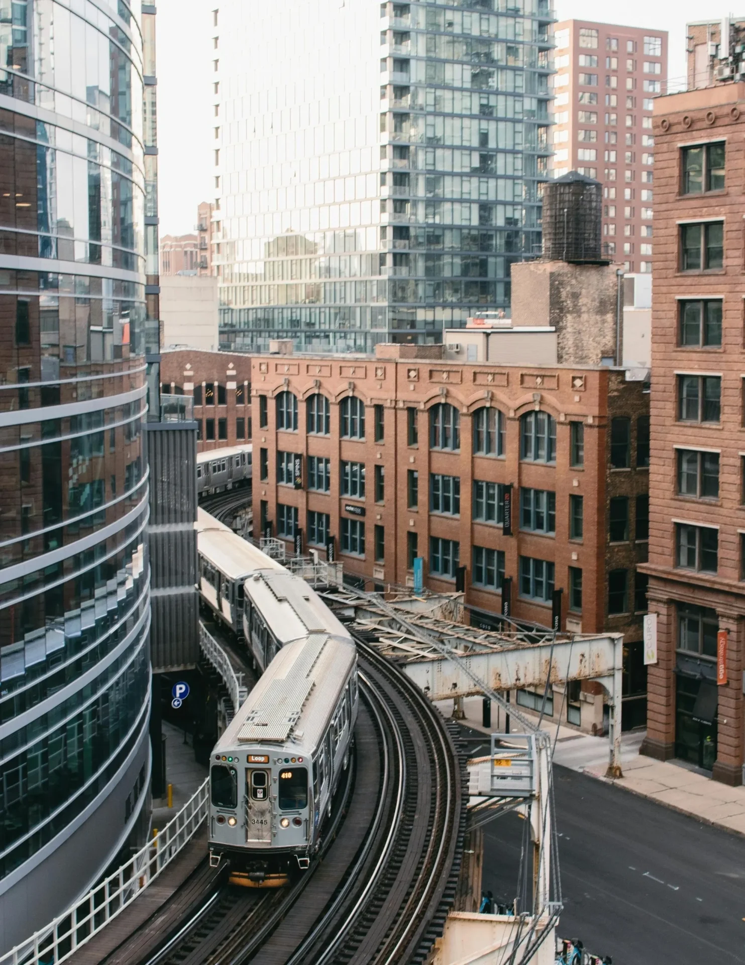 A train is coming down the tracks in front of some buildings.